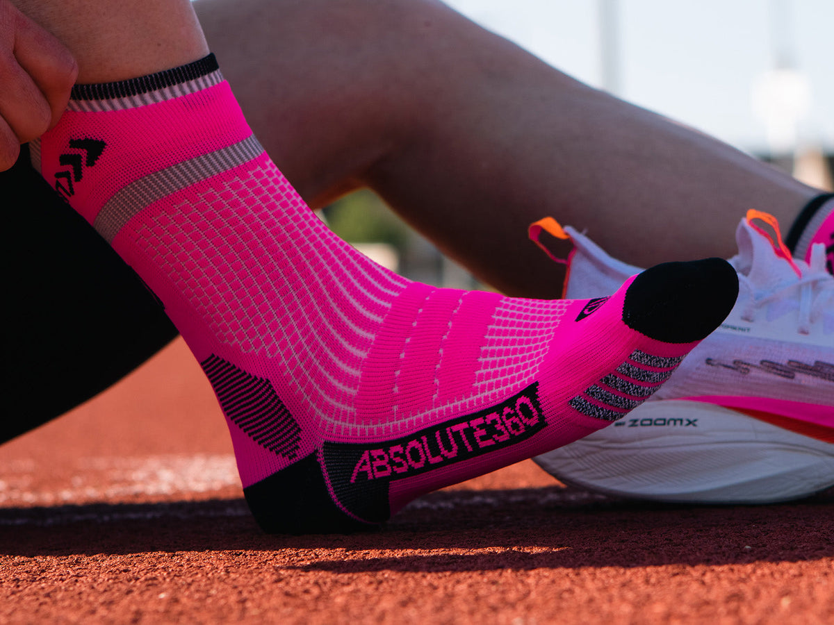 ABSOLUTE360 running sock worn beside a running shoe on a track