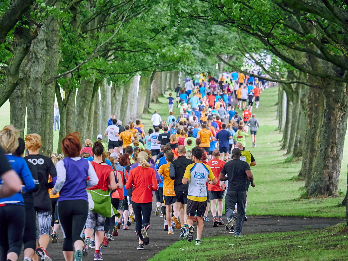 Runners taking part in a parkrun through a tree-lined park