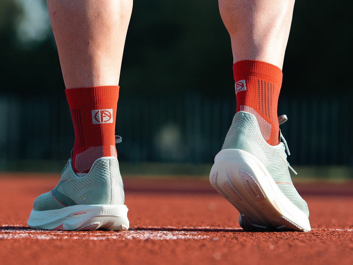 Runner wearing red ABSOLUTE360 performance running socks on a track