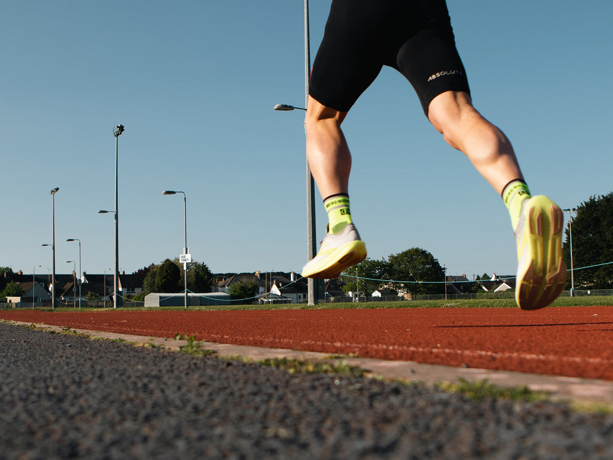 Runner performing a plyometric drill on a running track