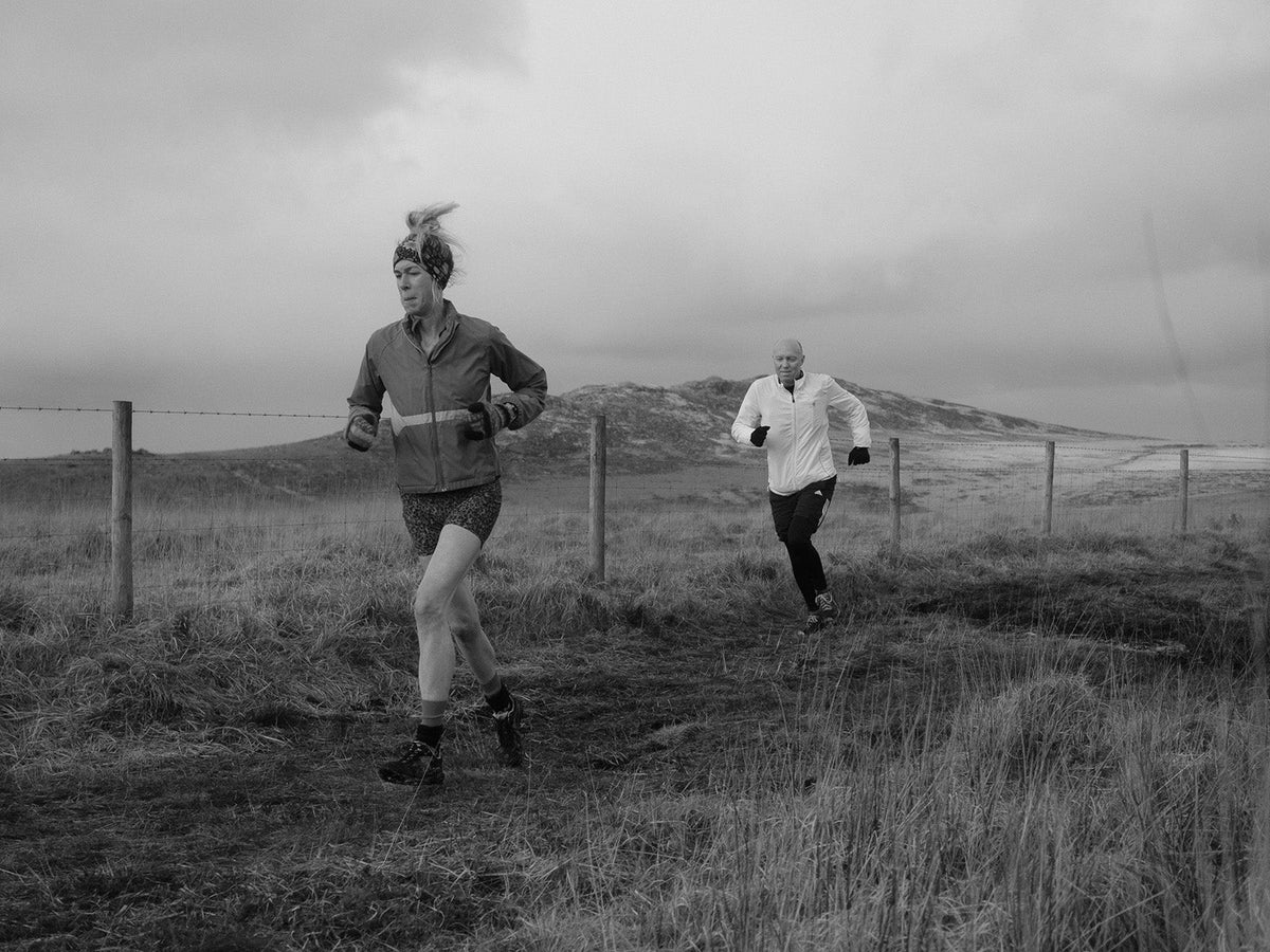 Two runners crossing exposed moorland in challenging conditions