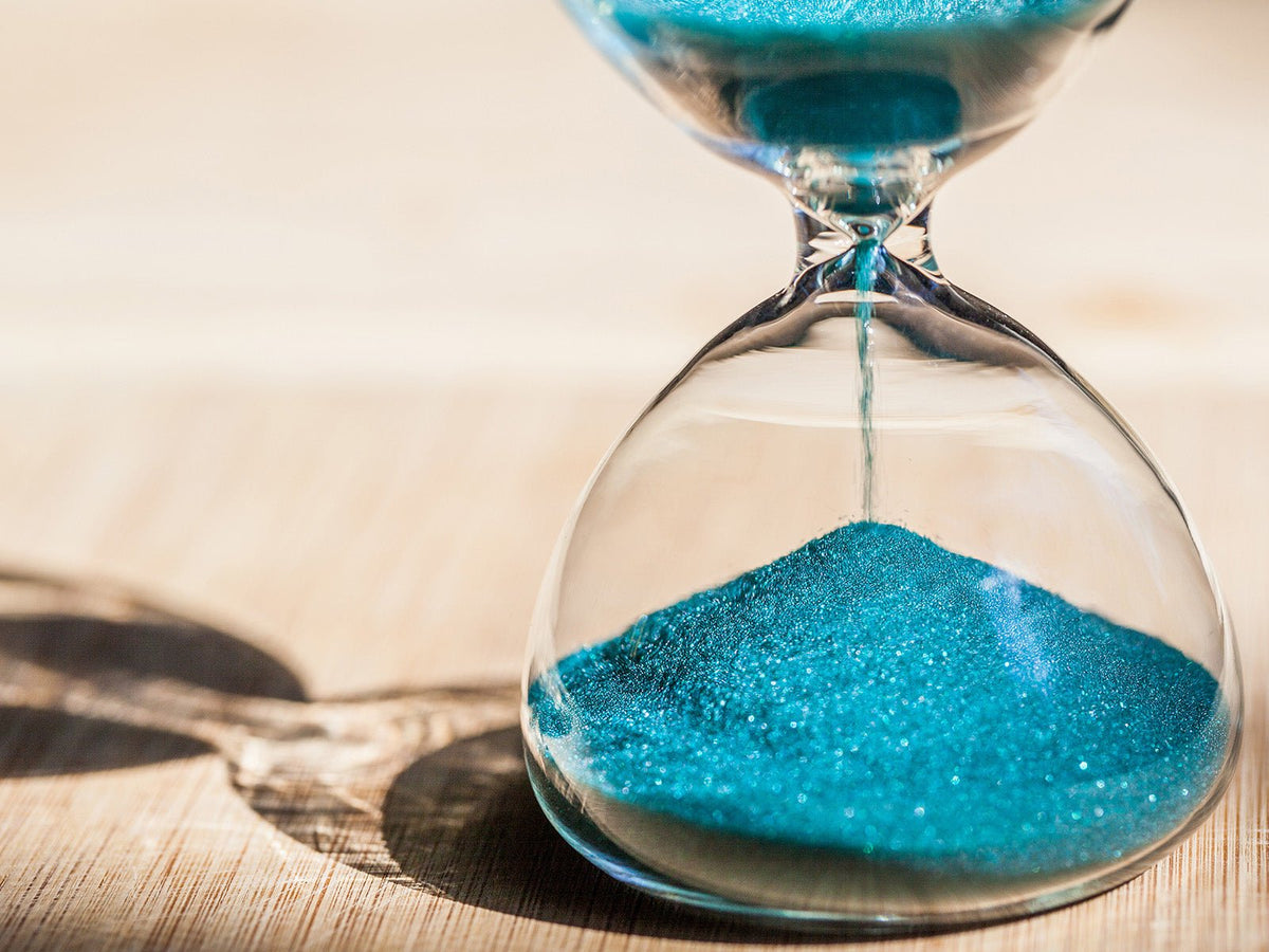 Blue sand flowing through an hourglass representing the passing of time