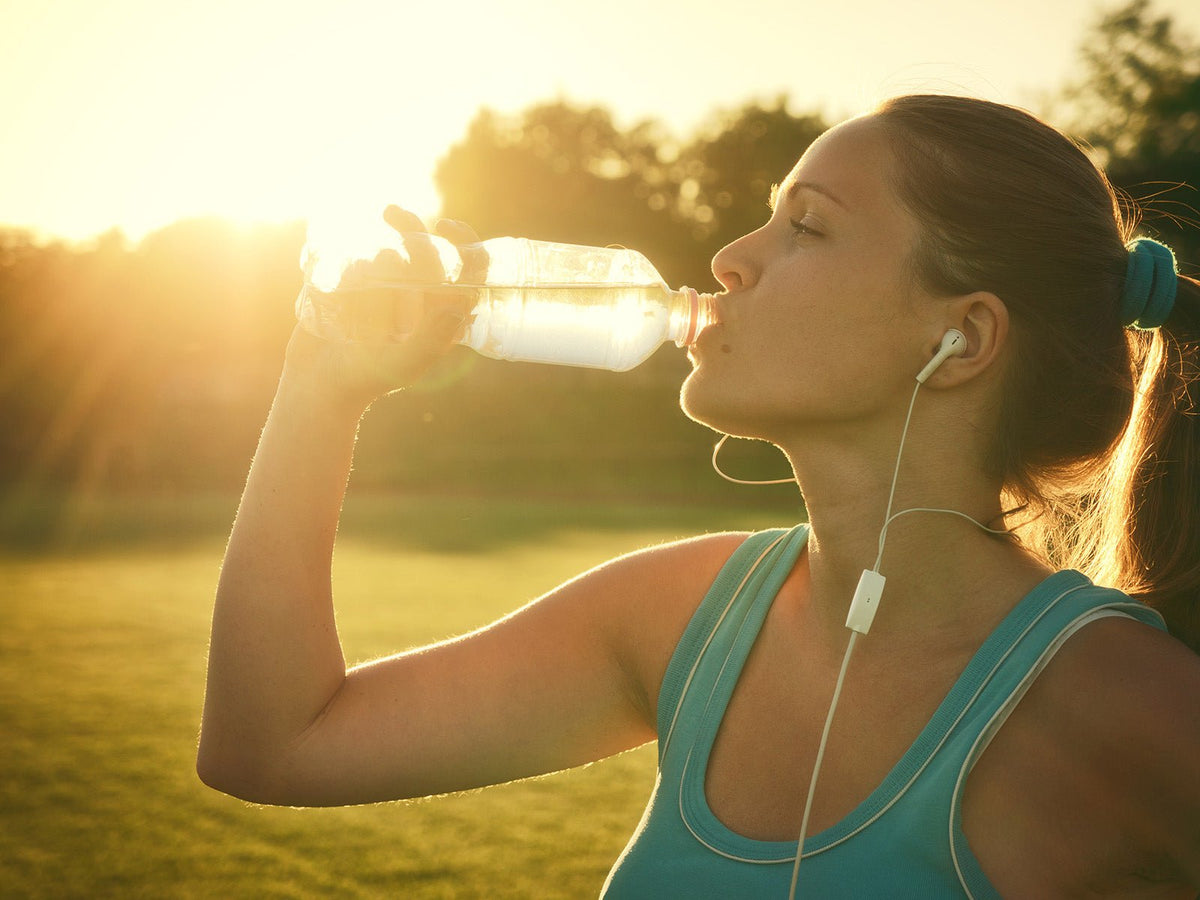 Runner drinking water outdoors after exercise to maintain hydration and support health and physical performance.