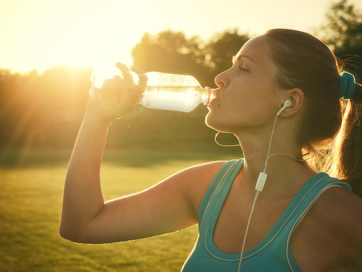 Runner drinking water outdoors after exercise to maintain hydration and support health and physical performance.