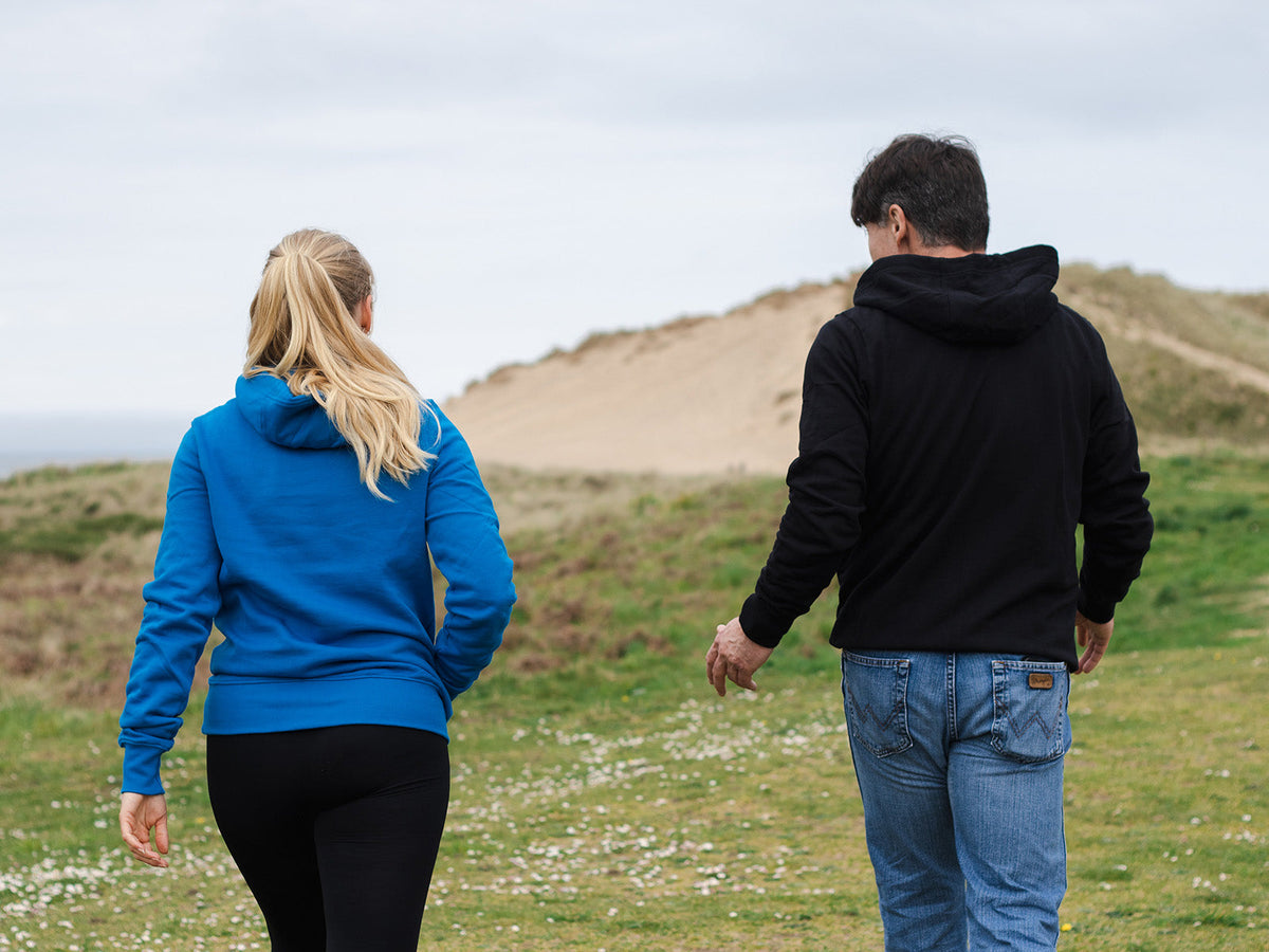 Two people walking through coastal sand dunes on a rest day