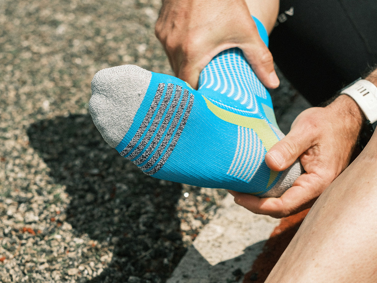 Runner adjusting a close-fitting ABSOLUTE360 Performance Running Sock